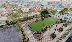Un jardín en la azotea con suelo a cuadros, palmeras y una zona de estar circular.