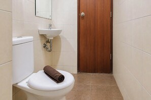 Un baño con inodoro, lavamanos y puerta de madera.