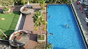 An aerial view of a hotel with a swimming pool, outdoor seating, and greenery. - Cozy Living 2Br At Vida View Makassar Apartment (Makassar)