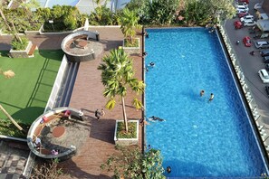 Vista aérea de un hotel con piscina, mobiliario exterior y vegetación.