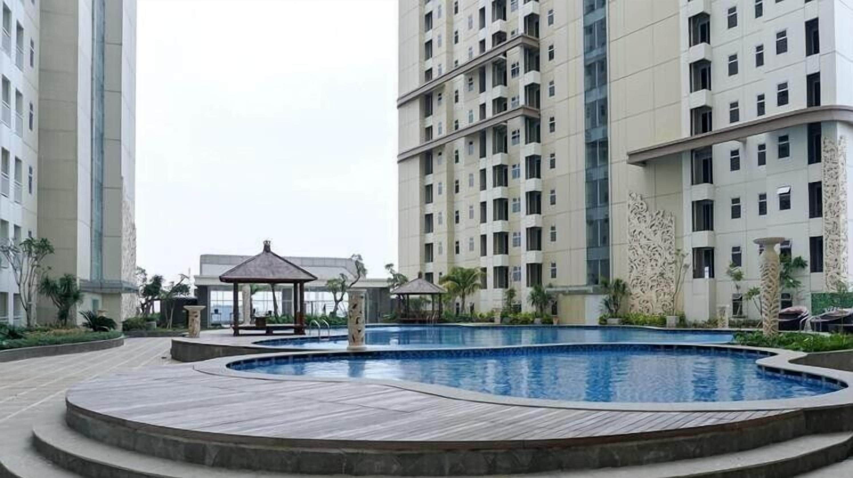 A swimming pool surrounded by a wooden deck, with high-rise residential buildings in the background.