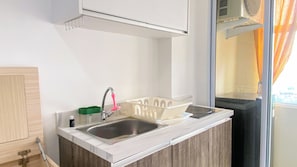A kitchen with a double sink, a green soap dish, and a window with curtains. - Good Choice And Homey Studio Apartment Vittoria Residence (Jakarta)
