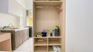 A modern bathroom with a wooden vanity, a sink, and a mirror. There is a shelf with toiletries and a sign listing travel destinations. - Good Choice And Homey Studio Apartment Vittoria Residence (Jakarta)