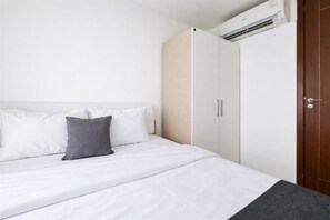 Ein Schlafzimmer mit Bett, Kissen, Kleiderschrank und Klimaanlage.