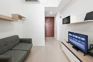 A modern living room with a grey sofa, a flat-screen TV, and a minimalist design. - Practical 1Br For 2 Pax At Vittoria Residence (Jakarta)