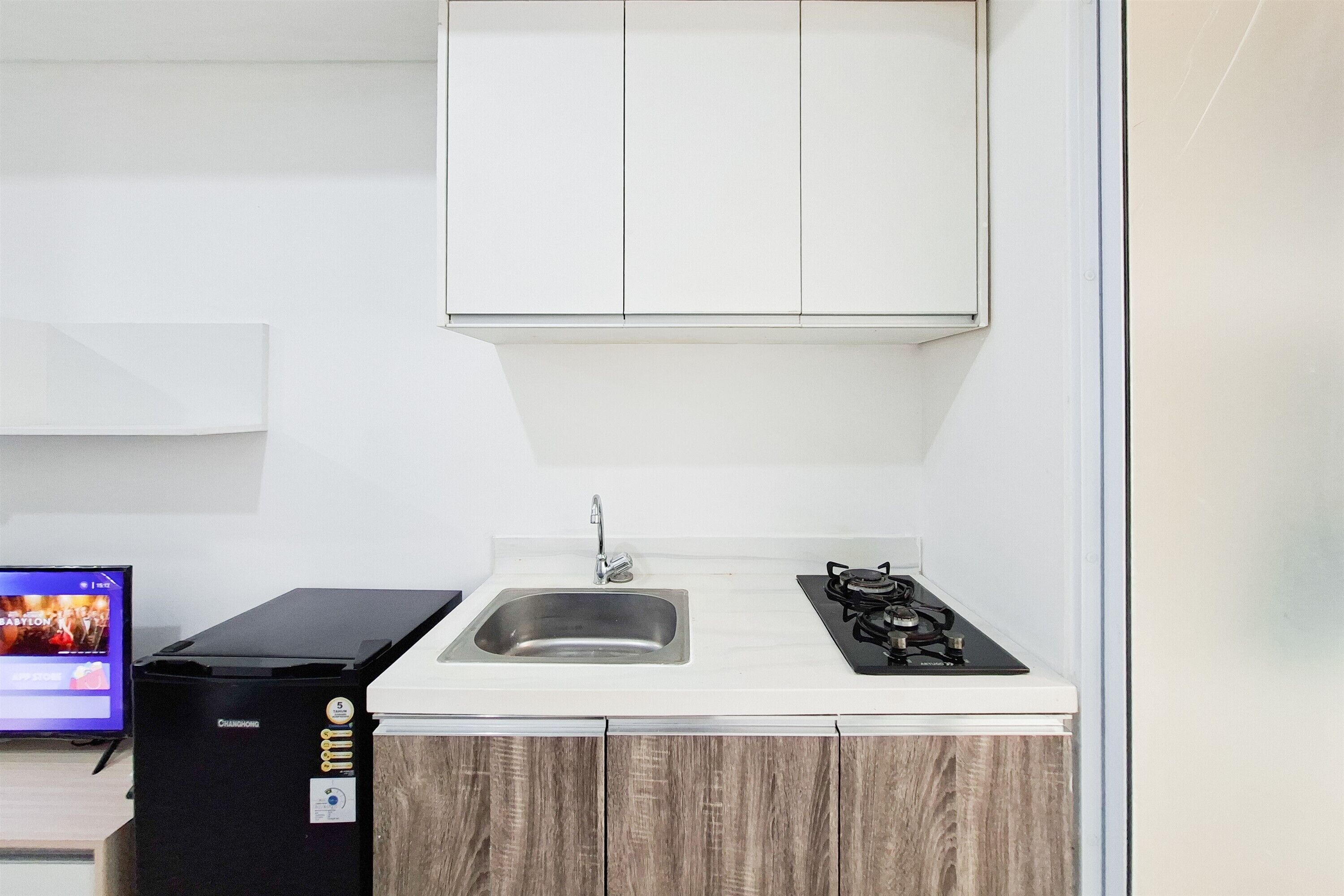 Una cocina compacta con lavamanos, estufa y refrigerador.
