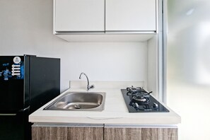 A kitchen with a sink, a stove, and a refrigerator. - Good And Warm 1Br Apartment At Vittoria Residence (Jakarta)