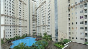A high-rise residential building with a swimming pool, balconies, and lush greenery. - Tranquil 1Br For 2 Pax At Vittoria Residence (Jakarta)