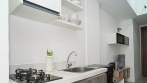A modern kitchen with a gas stove, a sink, and a microwave. - Homey And Best Place 2Br At Apartment Vittoria Residence (Jakarta)