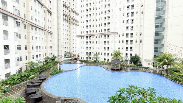 A residential building with a swimming pool, surrounded by greenery and a children's play area. - Homey And Best Place 2Br At Apartment Vittoria Residence (Jakarta)