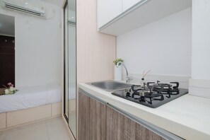 A modern kitchen with a gas stove, sink, and a small plant on the counter. - 1 Pax Functional Studio At Vittoria Residence (Jakarta)