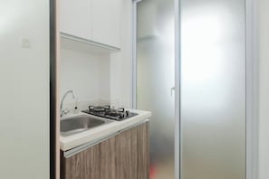 A kitchen with a sink, stove, and cabinets. - 1 Pax Functional Studio At Vittoria Residence (Jakarta)