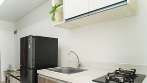 A compact kitchen with a black refrigerator, a sink, and a gas stove. - Affordable Price And Homey 1Br Apartment At Vittoria Residence (Jakarta)