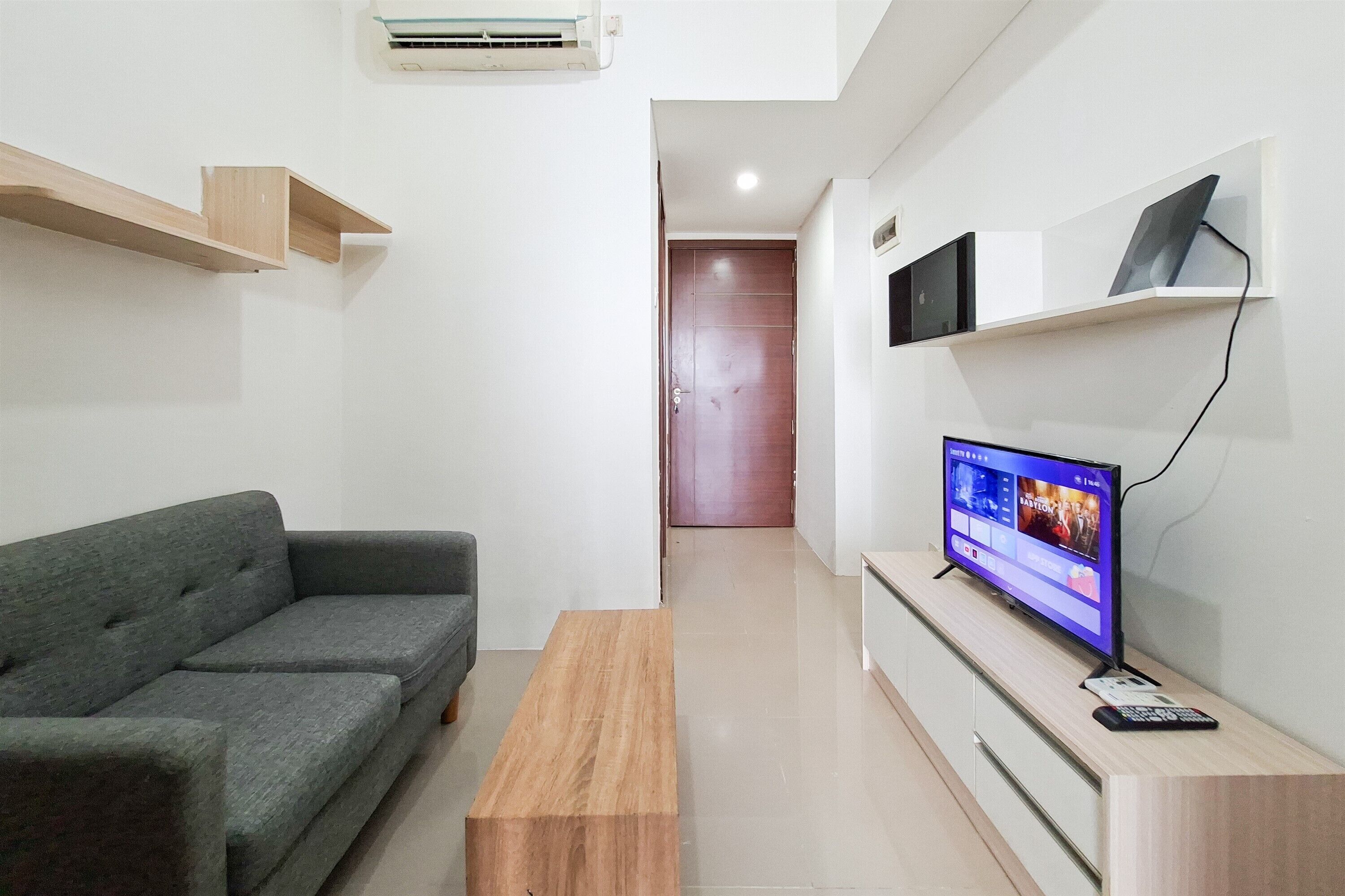 A modern living room with a grey sofa, wooden coffee table, TV, and built-in shelves.