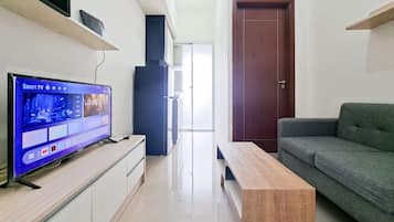 A modern living room with a flat-screen TV, a wooden coffee table, a grey sofa, and a wooden door.