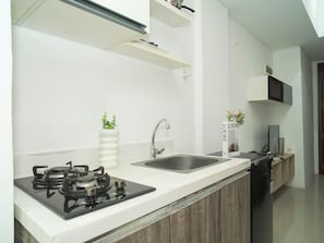 A modern kitchen with a gas stove, a sink, and a microwave. - Cozy And Good 2Br At Apartment Vittoria Residence (Jakarta)
