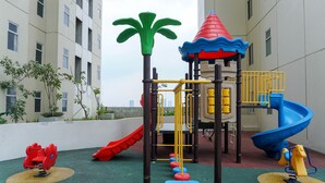 A playground with a slide, climbing structures, and a tower. - Cozy And Good 2Br At Apartment Vittoria Residence (Jakarta)