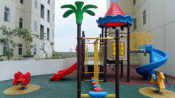 A playground with a slide, climbing structures, and a tower.