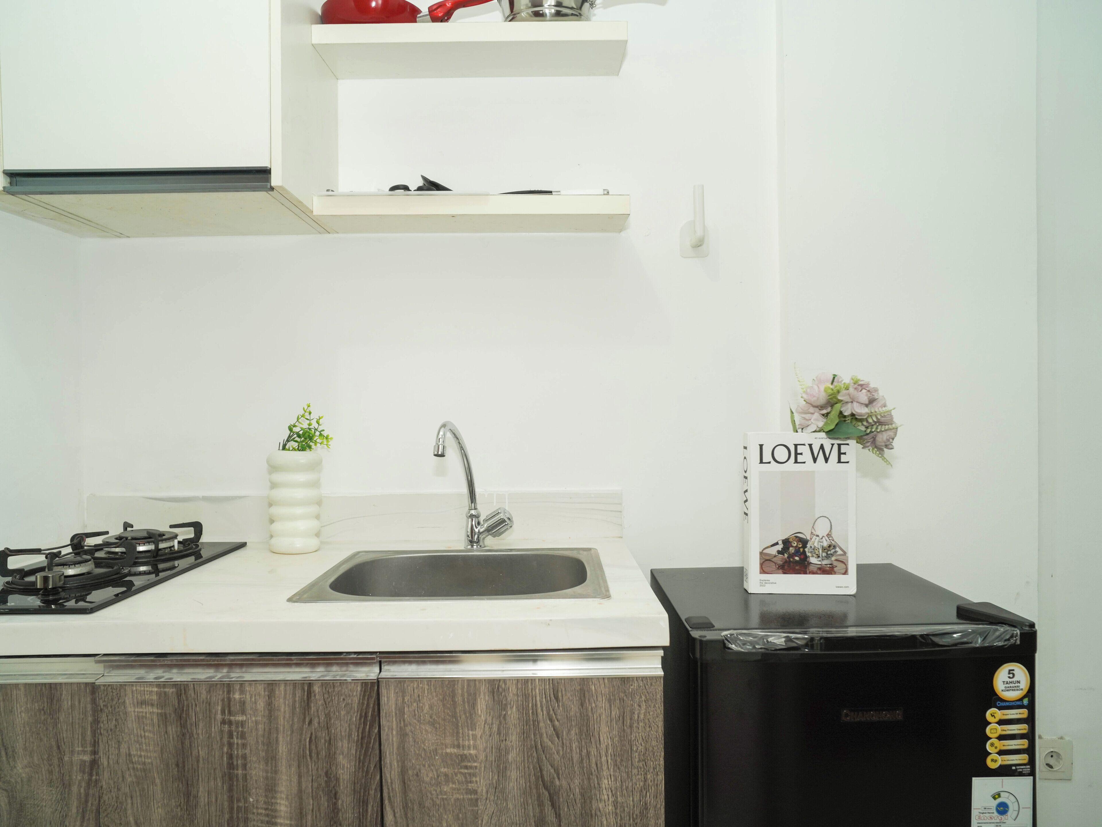 A kitchen with a gas stove, sink, and a black refrigerator.