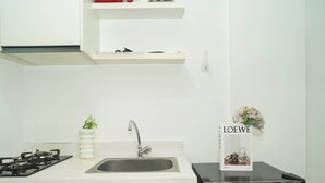 A kitchen with a gas stove, sink, and a black refrigerator. - Cozy And Good 2Br At Apartment Vittoria Residence (Jakarta)