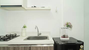 A kitchen with a gas stove, sink, and a black refrigerator.