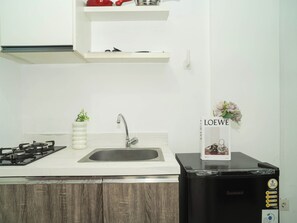 A kitchen with a gas stove, sink, and a black refrigerator. - Cozy And Good 2Br At Apartment Vittoria Residence (Jakarta)