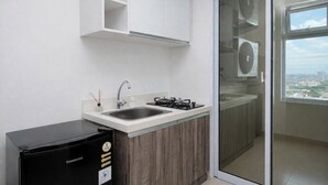 A kitchen with a sink, stove, and a black refrigerator. - Relaxing And Cozy 1Br Apartment At Vittoria Residence (Jakarta)