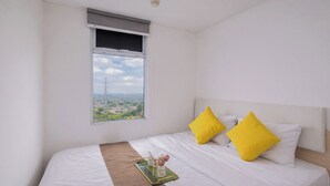 A bedroom with a bed, a window with a view, and a bedside table with a tray. - Relaxing And Cozy 1Br Apartment At Vittoria Residence (Jakarta)