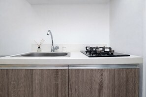 Eine Küche mit Spüle aus Edelstahl, einem Gasherd und Holzschränken.