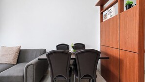 A modern kitchen with a dining table, chairs, a grey sofa, and a wooden cabinet with decorative items. - Enjoy Living In Comfortable 2Br At Apartment West Vista (Jakarta)