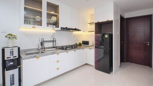 A modern kitchen with white cabinets, a built-in microwave, a refrigerator, and a water dispenser. - Enjoy Living In Comfortable 2Br At Apartment West Vista (Jakarta)