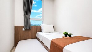 A hotel room with a bed, a window with curtains, a view of the city, and a small table with a plant. - Enjoy Living In Comfortable 2Br At Apartment West Vista (Jakarta)