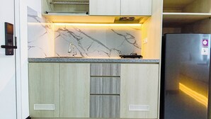 A kitchen with a marble countertop, a built-in sink, and a stainless steel refrigerator. - Modern Style Studio At Westown View Surabaya Apartment (Surabaya)