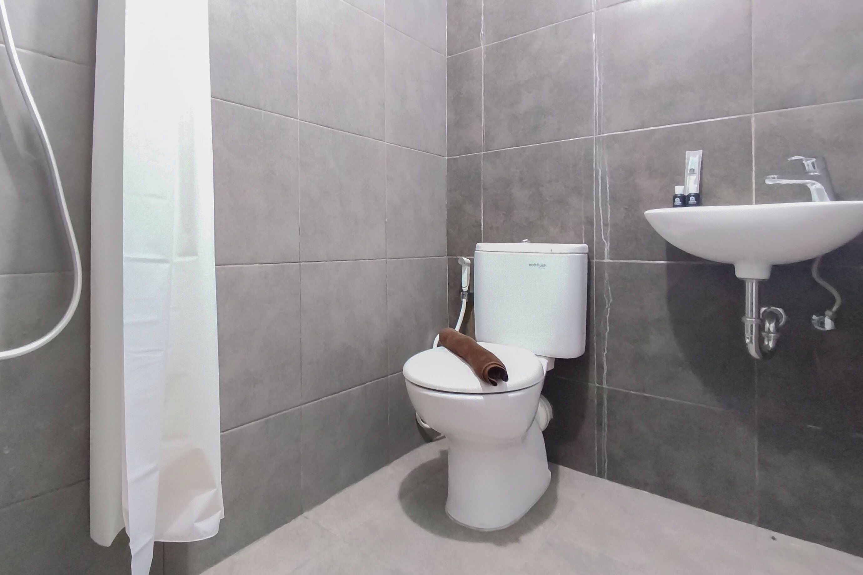 A bathroom with a toilet, a shower curtain, and a sink.