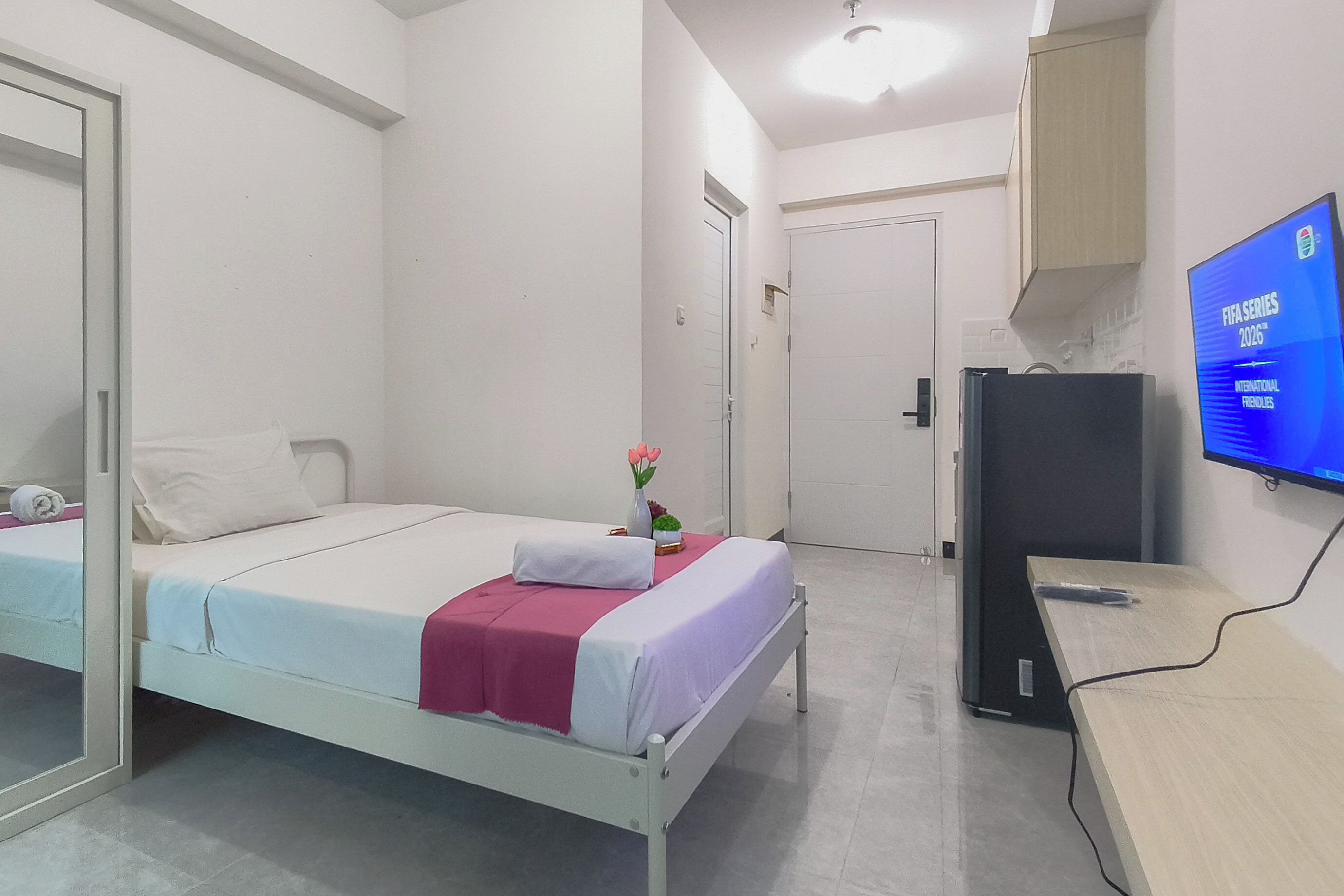 Een hotelkamer met een bed, bureau, televisie en kledingkast.