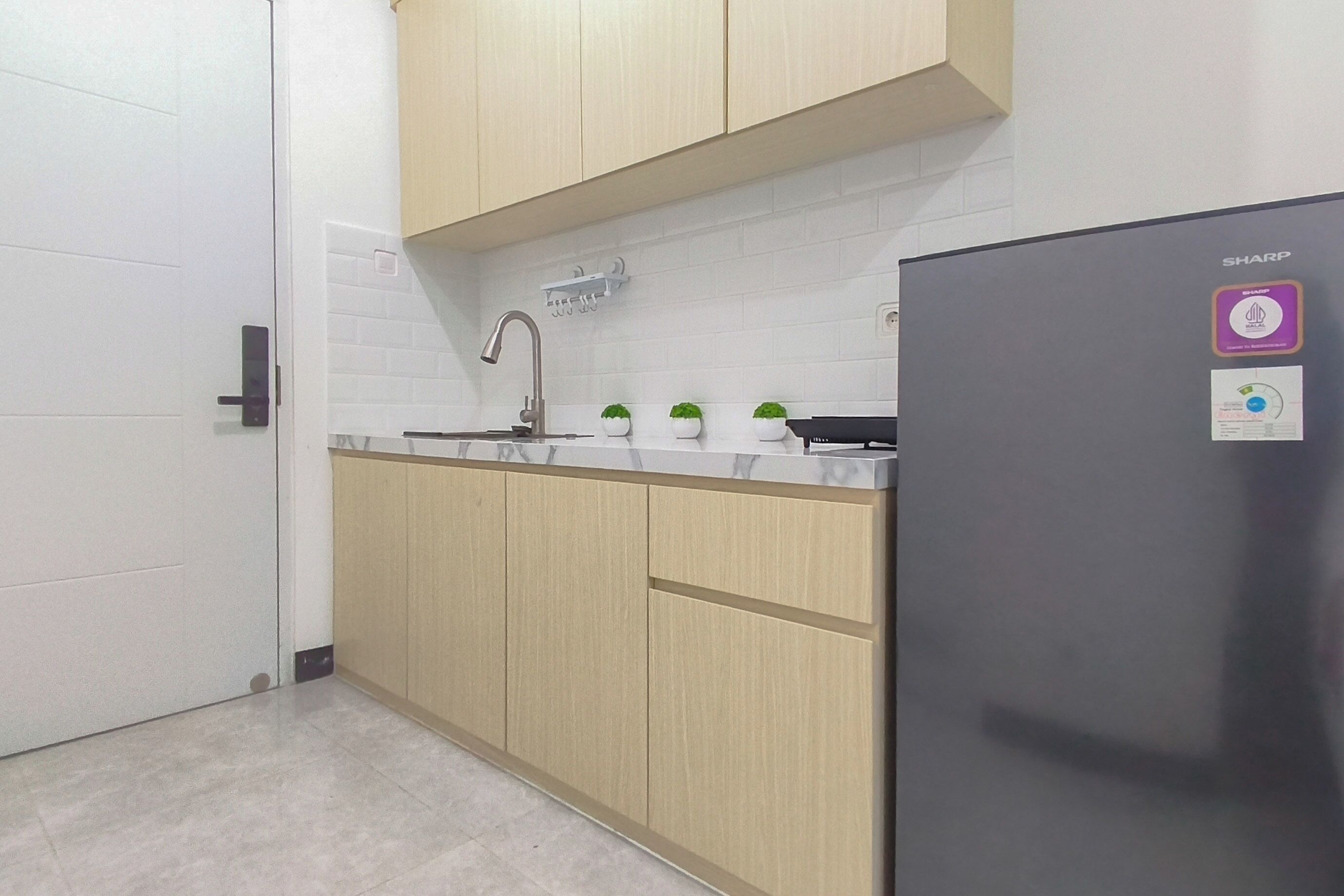 A modern kitchen with light wood cabinets, a stainless steel refrigerator, and a white tiled backsplash.