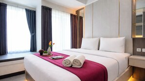 A hotel room with a large bed, a window with curtains, a bedside table, and a nightstand. - Serene Studio At Westown View Surabaya Apartment (Surabaya)