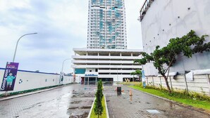 A multi-story building with a parking garage, a green median strip, and a sign for SAIM. - Serene Studio At Westown View Surabaya Apartment (Surabaya)