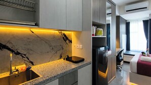 A modern kitchen with a marble backsplash, built-in appliances, and a countertop with a sink. - Serene Studio At Westown View Surabaya Apartment (Surabaya)
