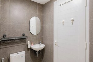 A bathroom with a sink, mirror, and toilet. - Pleasureable Studio Apartment At Westown View Surabaya (Surabaya)