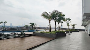 Eine Dachterrasse mit Pool, Palmen und Blick auf die Stadt.