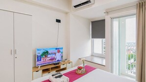 Habitación de hotel con cama, televisión, armario y ventana con vistas.