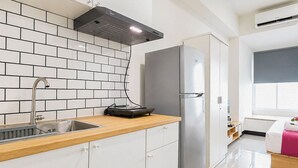 A modern kitchen with a stainless steel refrigerator, a built-in oven, and a sink with a wooden countertop. - Pleasureable Studio Apartment At Westown View Surabaya (Surabaya)