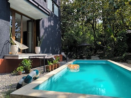 Una casa moderna con piscina, plantas en macetas y una hamaca.