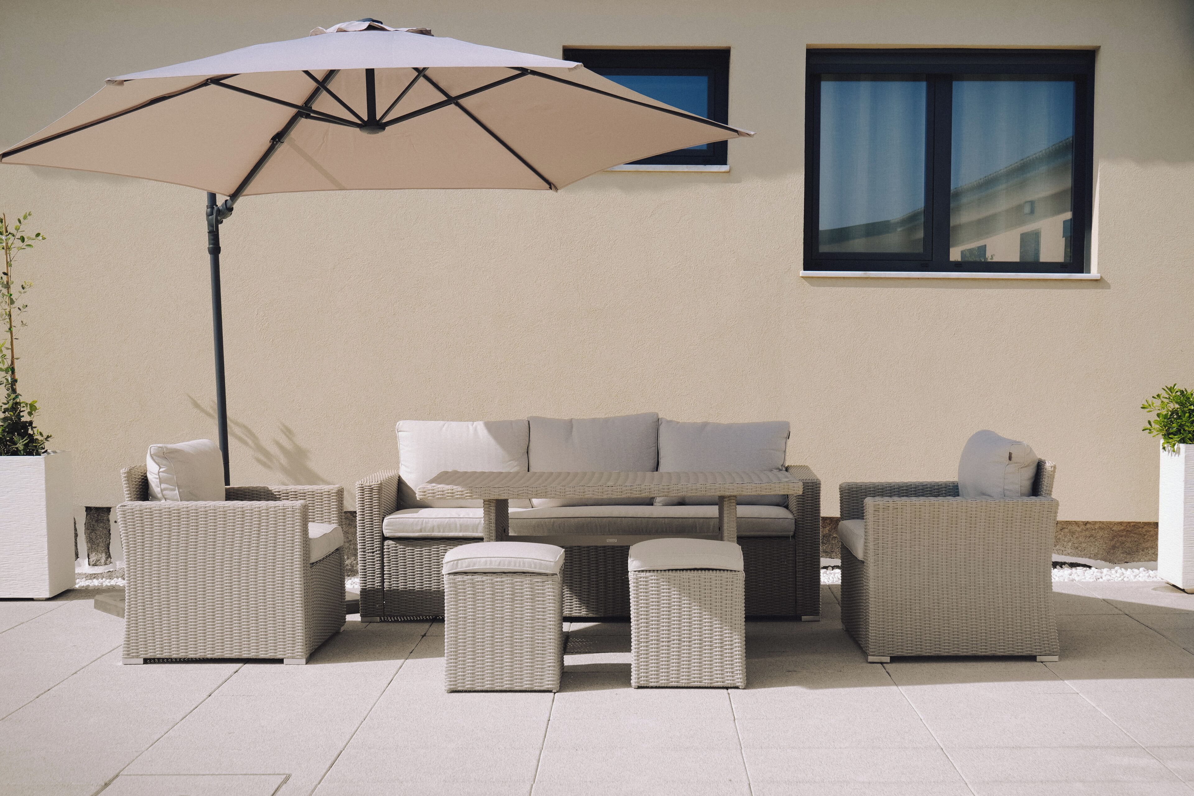Een terras met een zithoek, poefjes en een grote parasol.