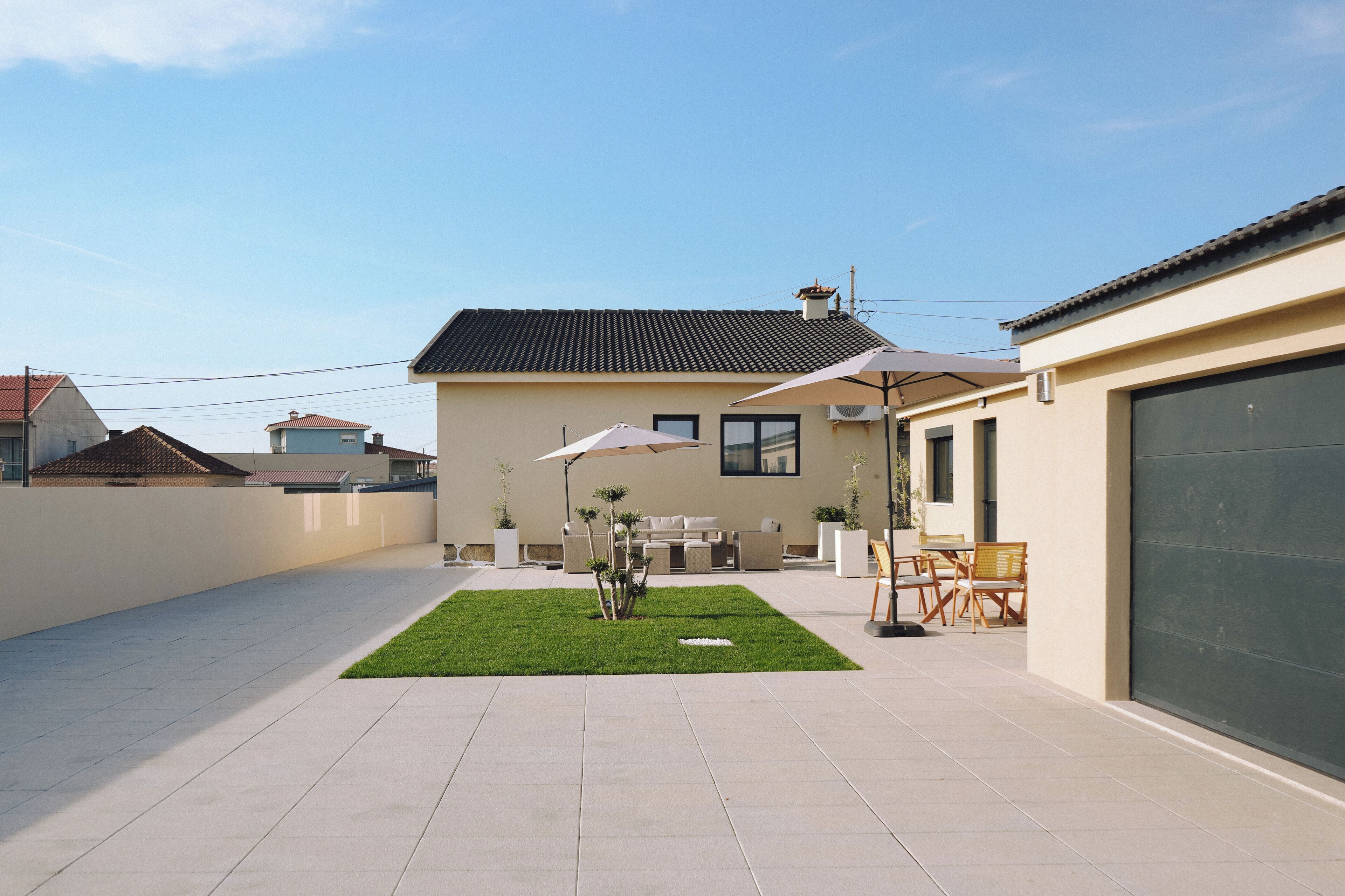 A modern house with a patio, outdoor furniture, and a garage.