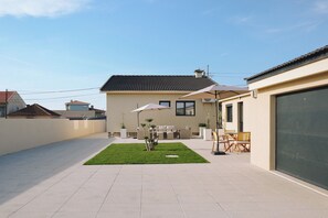A modern house with a patio, outdoor furniture, and a garage. - Villa d'Avó Dalva Beach modern family house, 50 m from the Ocean (Vila Chã)