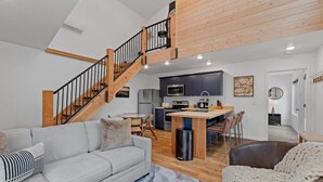 A modern living space with a staircase, a kitchen, and a dining area. - Cloudview Lodge  Retreat (Rapid City)