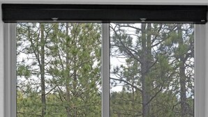 A bedroom with a large window, a bed, and a view of a forest. - Cloudview Lodge  Retreat (Rapid City)
