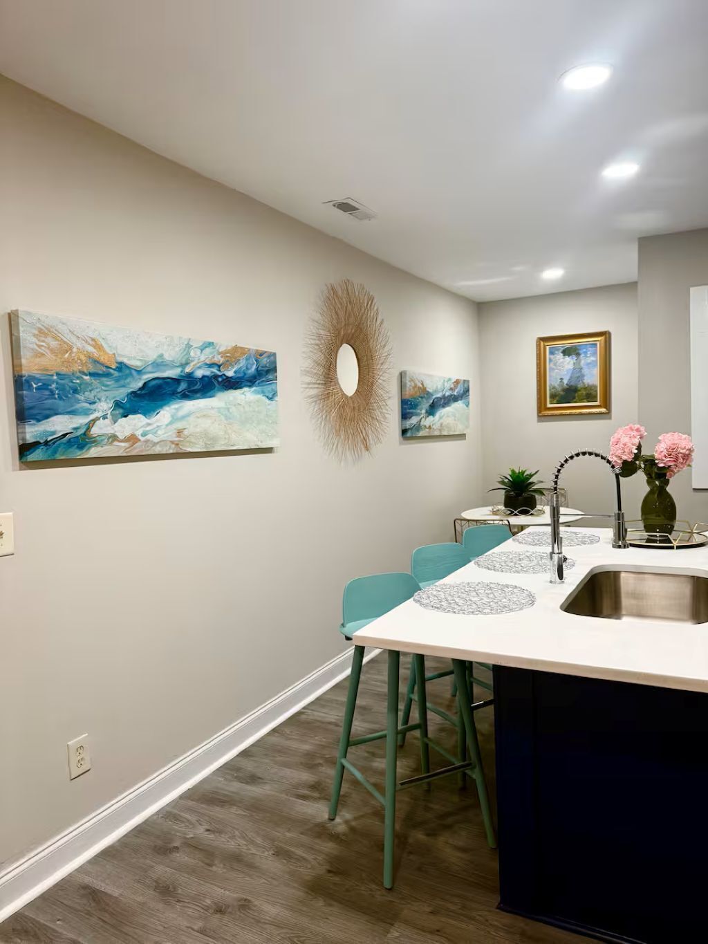 A modern kitchen with a central island, bar stools, a sink, and decorative wall art.